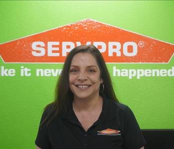 A SERVPRO employee dressed in SERVPRO attire standing in front of a green wall