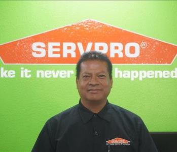 A SERVPRO employee standing in front of  a green wall with SERVPRO logo