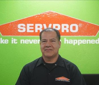 A  man standing in front of a SERVPRO wall, in SERVPRO attire